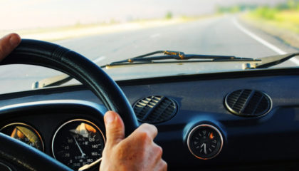 hands on steering wheel of nice car on road