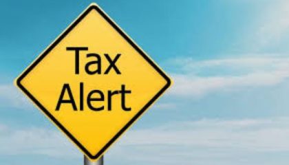 yellow road sign saying tax alert against blue sky